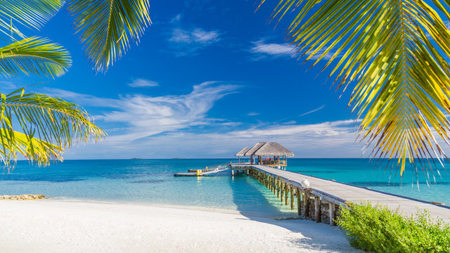 Bahamian beach with a wooden pier and thatched pavilion