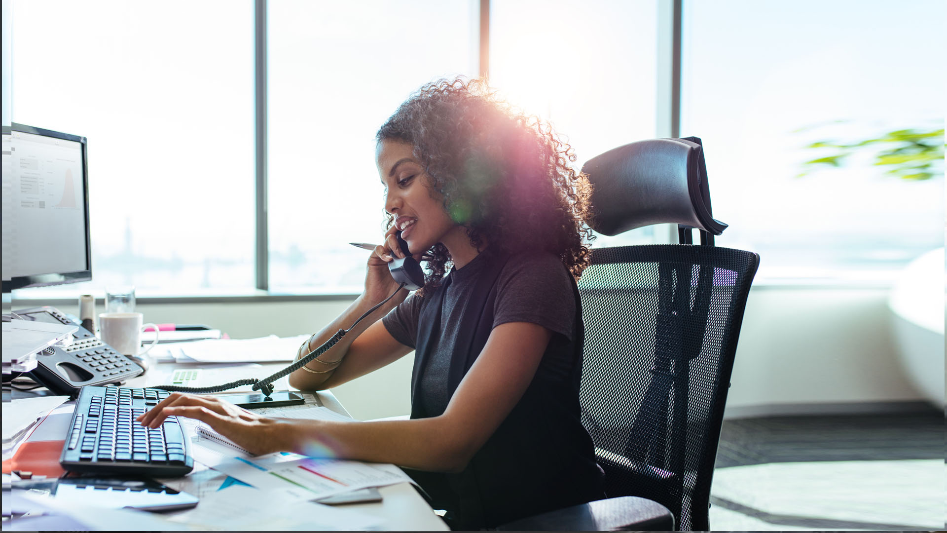 Professional speaking on the phone while working at an office desk
